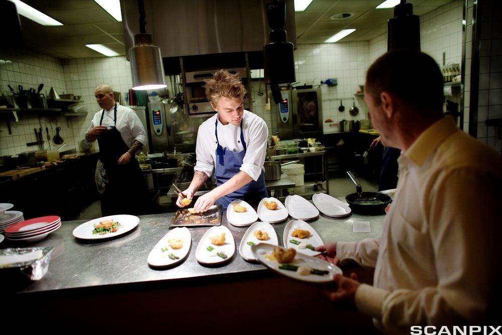 En kokk og en servitør i arbeid på en restaurant. Foto.