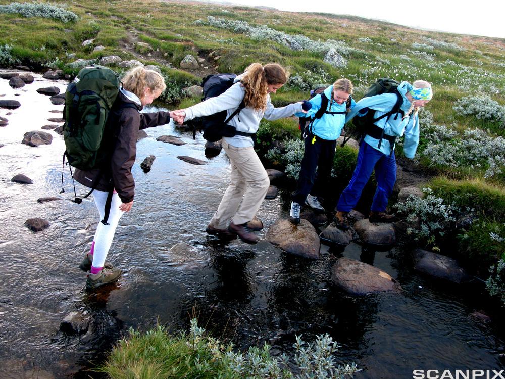 ungdommer på fottur, krysser ei lita elv