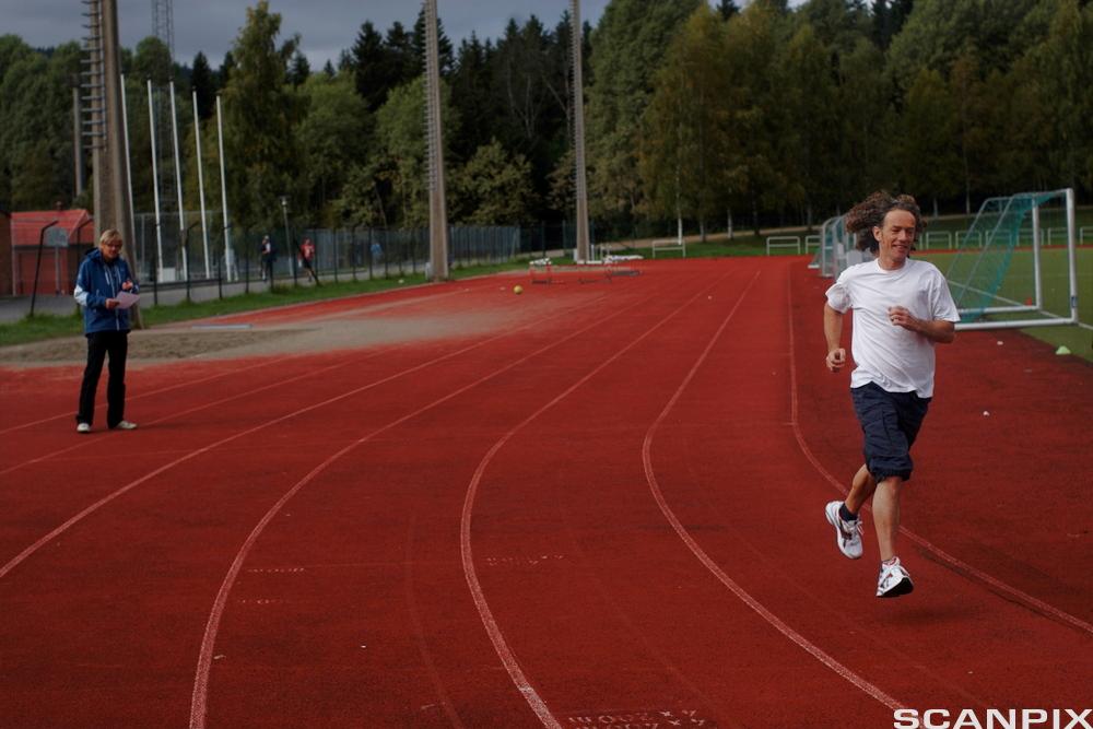 Mann joggar på friidrettsbane. Foto.
