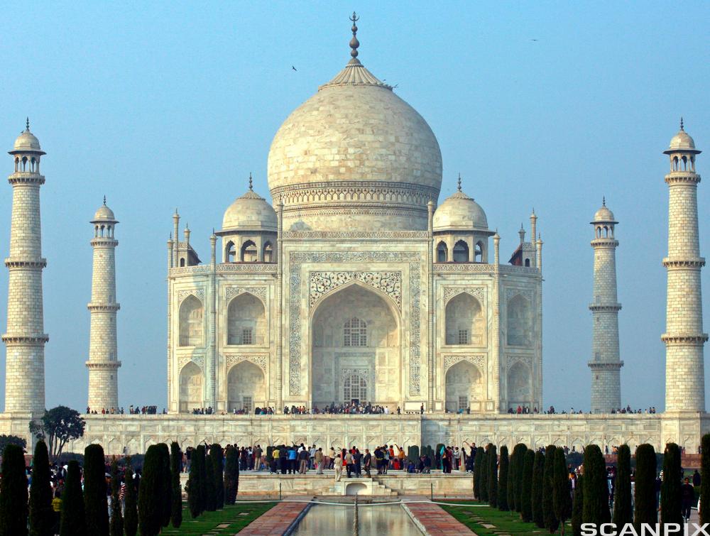 Tourists stand in front of the historic Taj Mahal in Agra. Photography.