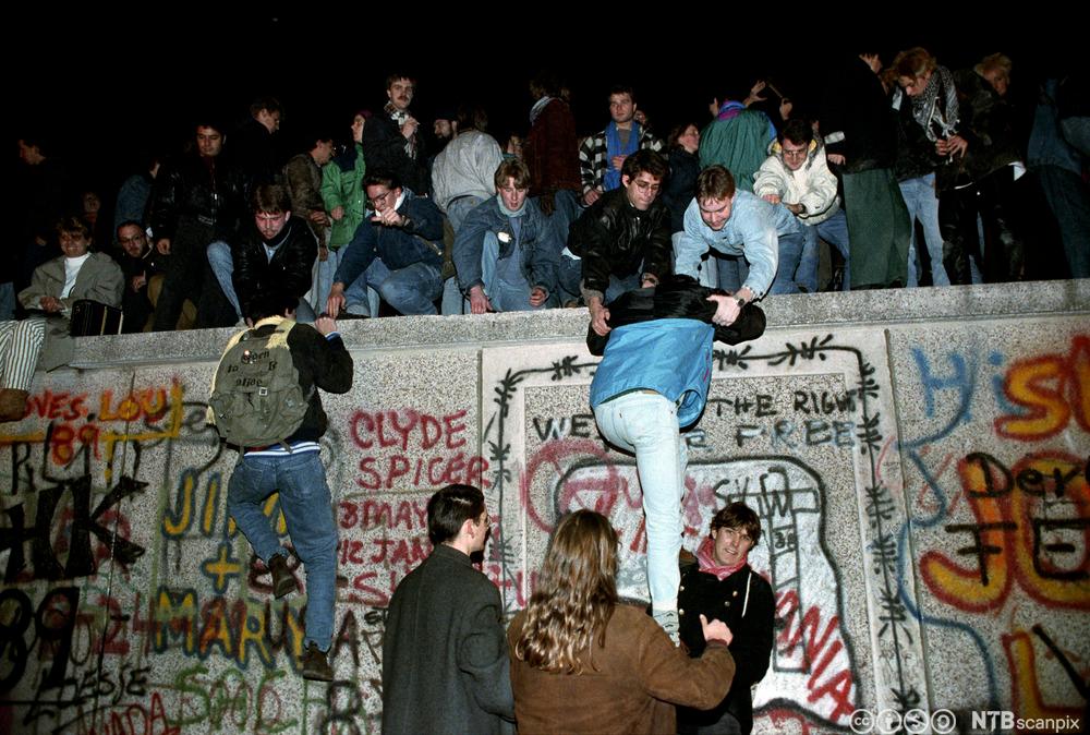 Ungdommer klatrer opp på Berlinmuren november 1989