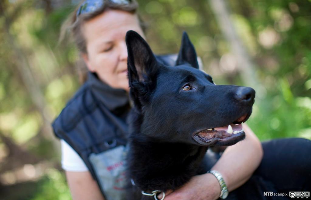 Kvinne med armen rundt hunden sin. Foto.