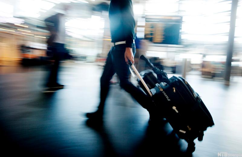Reisende som triller en koffert på flyplass. Foto