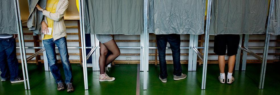 Personer i stemmeavlukker ved skolevalg. Foto.