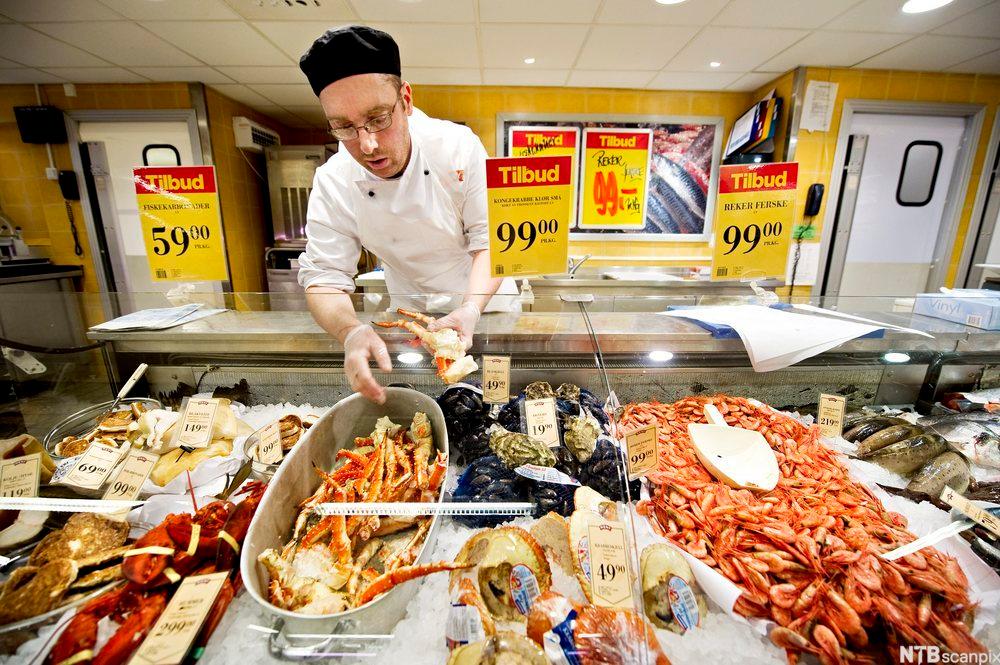 En fiskehandler i fiskedisken. Foto.