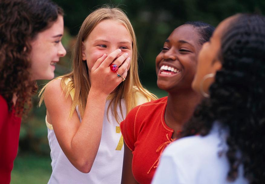 A group of four people standing outdoors, engaged in a conversation. Their faces are obscured for privacy. Photo.