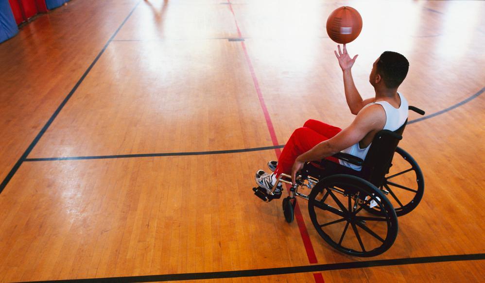 Mann i rullestol i gymsal med basketball. Foto.