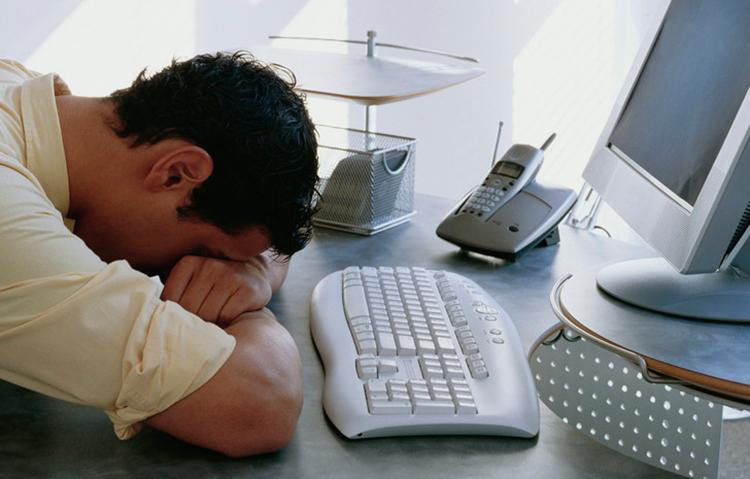 Mann sover fremfor datamaskin. Foto.