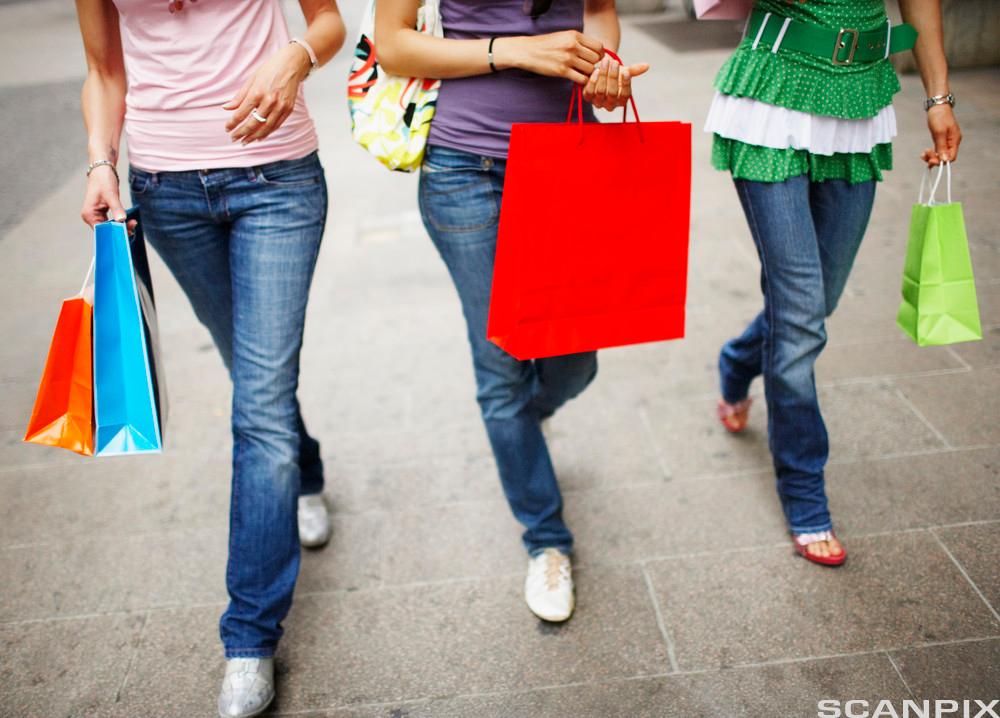 Tre kvinner går med bæreposer fra shopping. Foto.