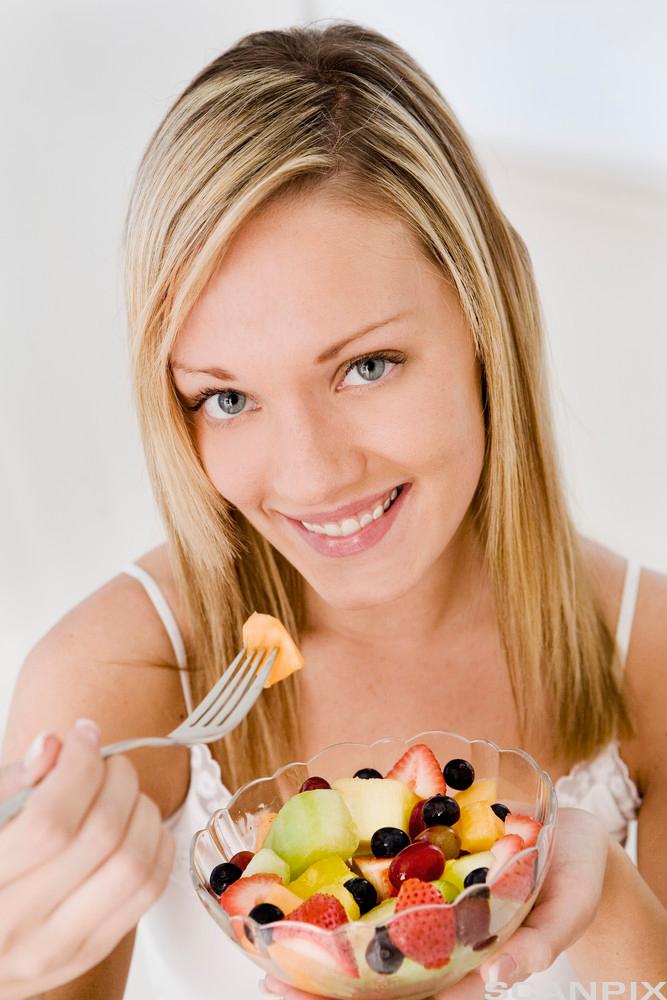 En jente spiser en fruktsalat. Foto.