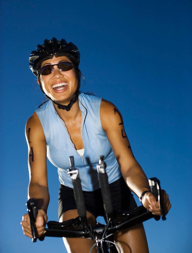 Kvinne på sykkel smiler bredt. Foto.