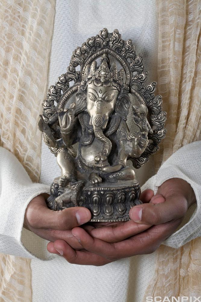 Hender holder statue av elefantguden Ganesha. Foto.