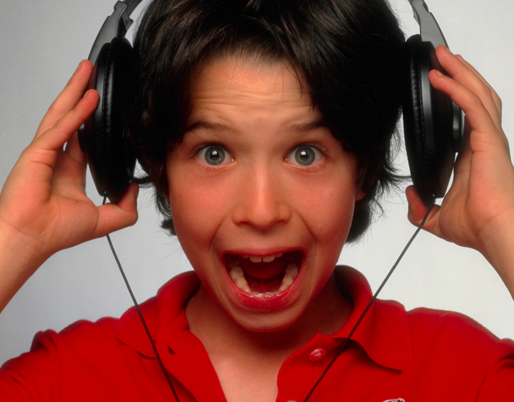 Ung gut lyttar til høg musikk gjennom øyretelefonar. Foto.