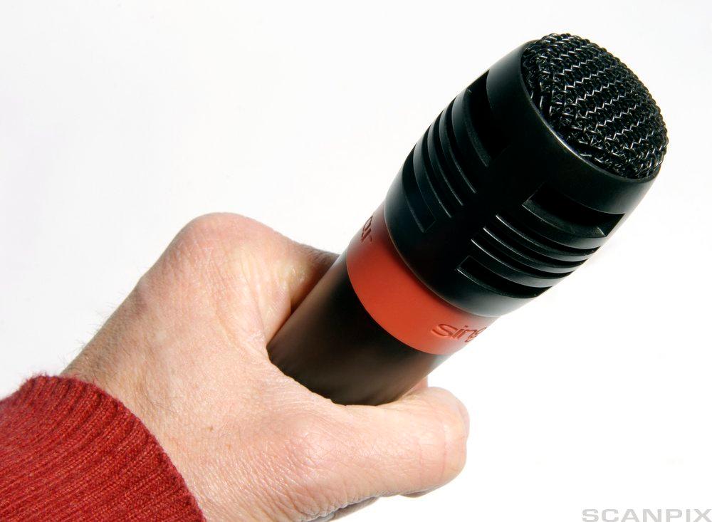 Hånd som holder mikrofon. Fotografi.