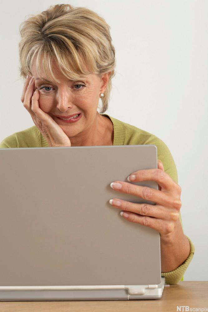 Ei kvinne studerer ein PC-skjerm. Ho ser frustrert ut.