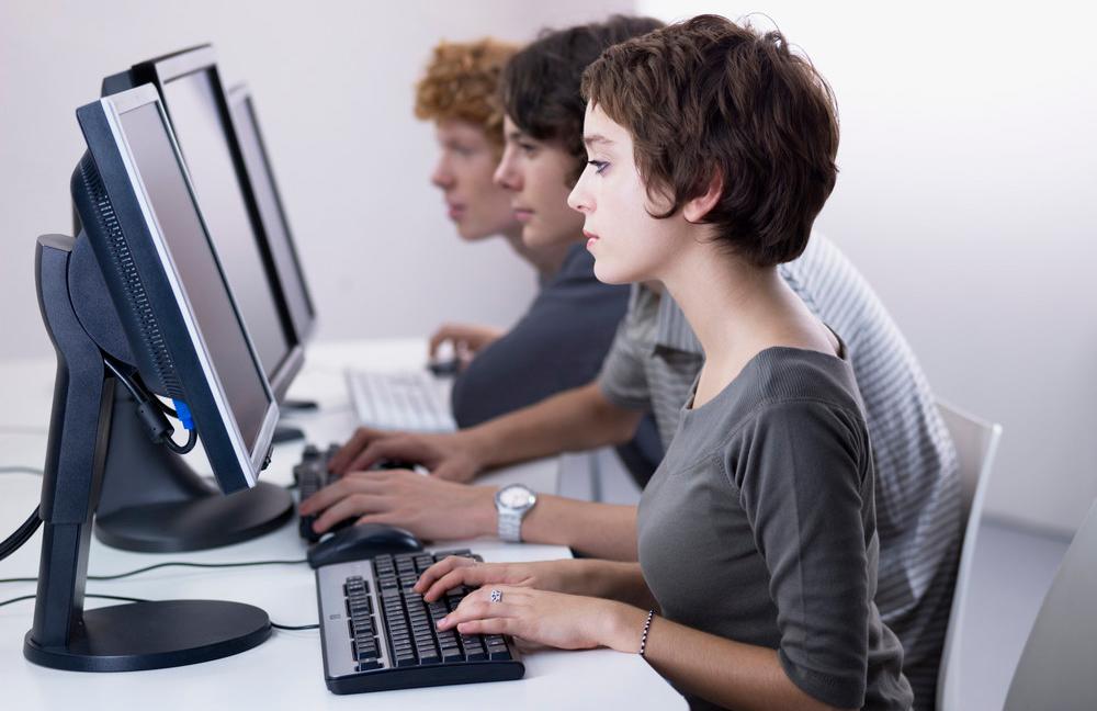 Tre unge mennesker leser på skjerm mens de skriver på tastaturet. Foto.