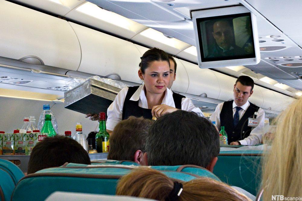 Flyvertinne som serverer drikke til flypassasjerar. Foto.