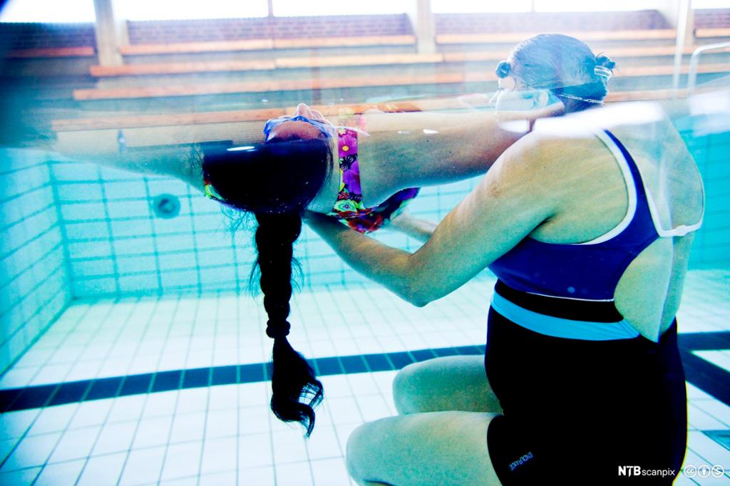 Kvinne får hjelp til å lære og svømme. Foto.
