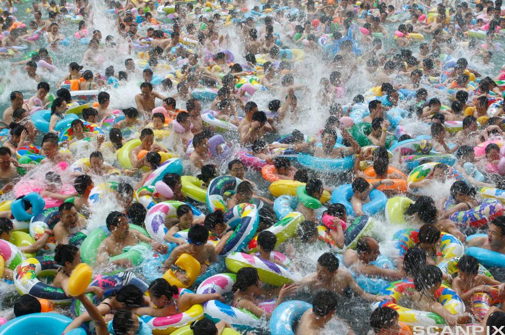Ei stor mengde menneske og baderingar i eit overfylt symjebasseng i sommarvarmen i Suining, Kina. Foto.