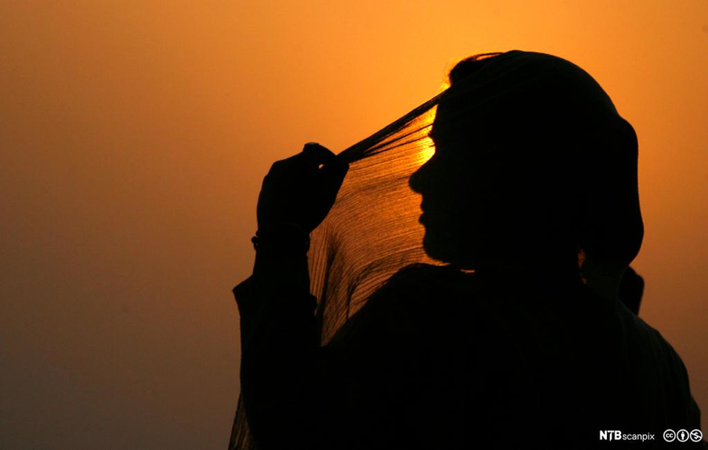 Indian woman adjusts her scarf as the sun sets