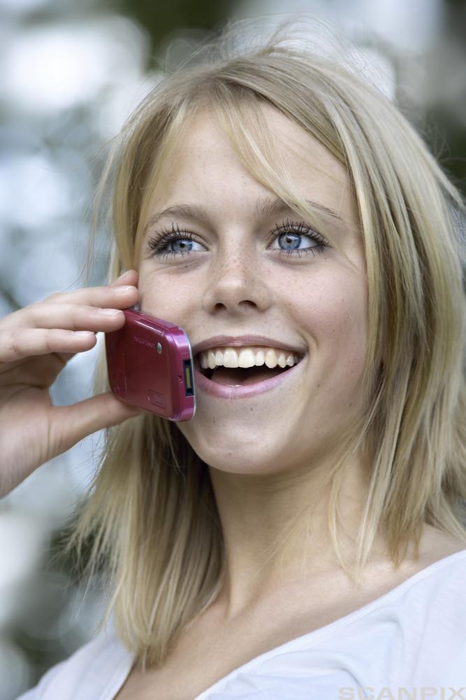 En ung jente snakker i mobiltelefon. Foto.