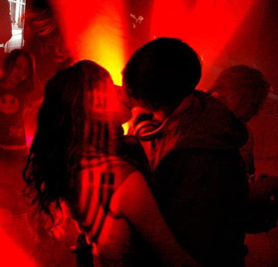 Ungt par som kysser på fest. Foto.