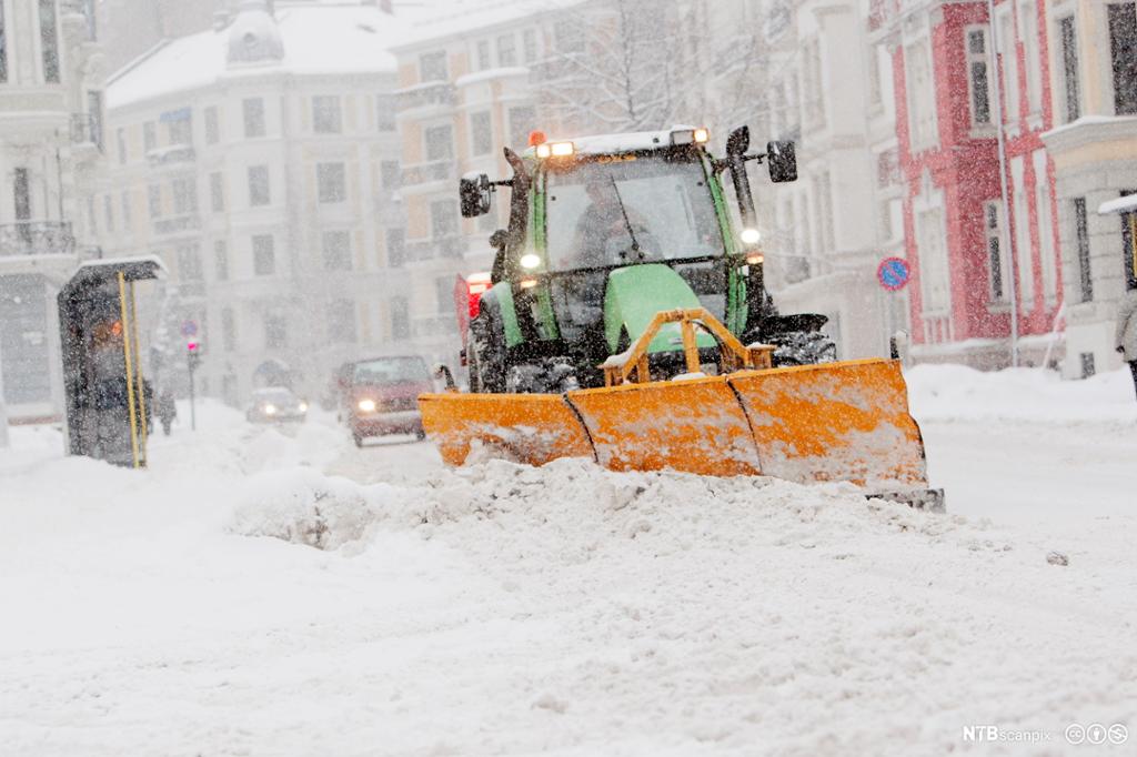 Traktor rydder snø i en bygate. Foto.