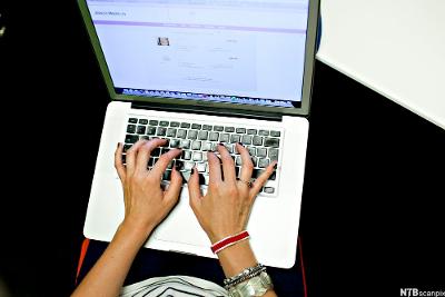 Hender på tastaturet på ei berbar datamaskin. Foto.