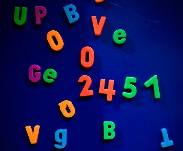 Magneter formet som tall og bokstaver, i forskjellige farger. Foto.