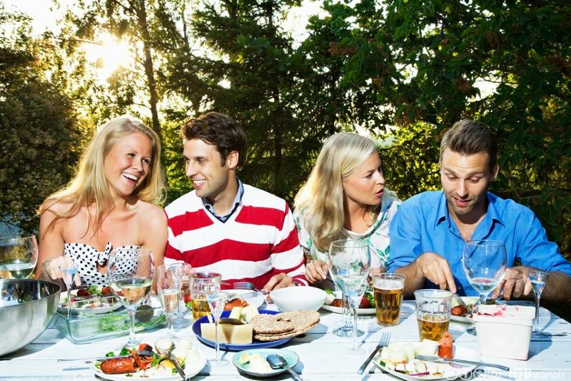Fire unge personer spiser middag ute i hagen. Foto.