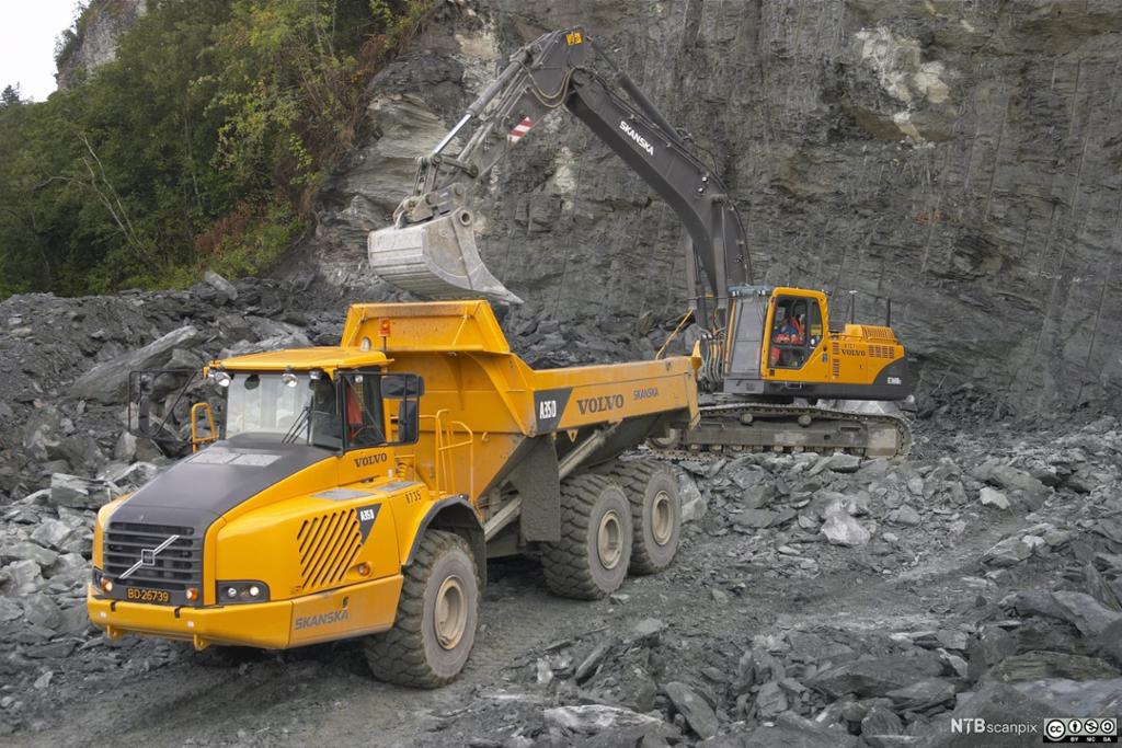 Gravemaskin og dumper fjerner stein. Foto.