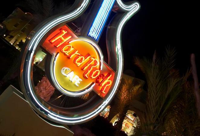 Picture of a neon sign with a guitar and the words Hard Rock Café. 