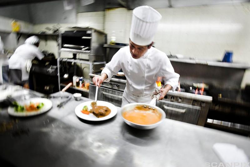 Kokk legger opp mat på et restaurantkjøkken. Foto.