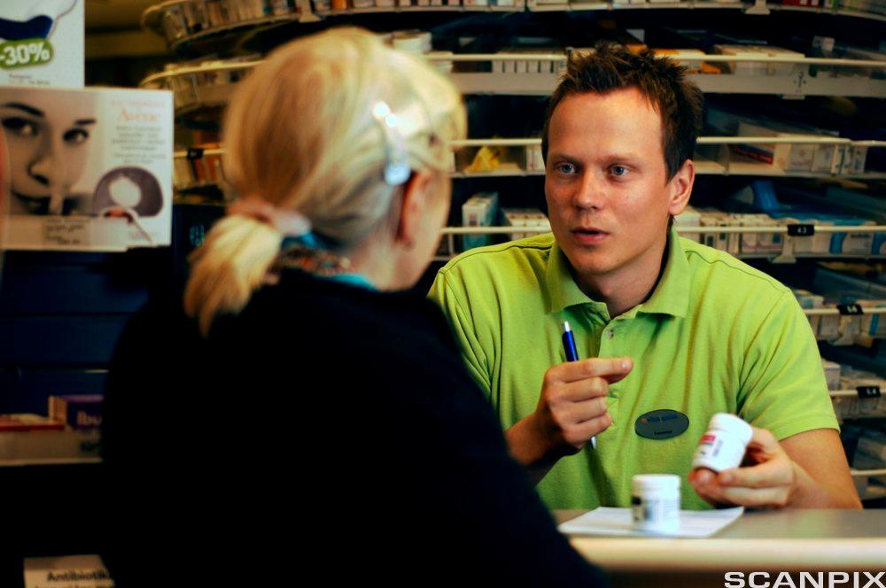 Apotektekniker snakker med kunde