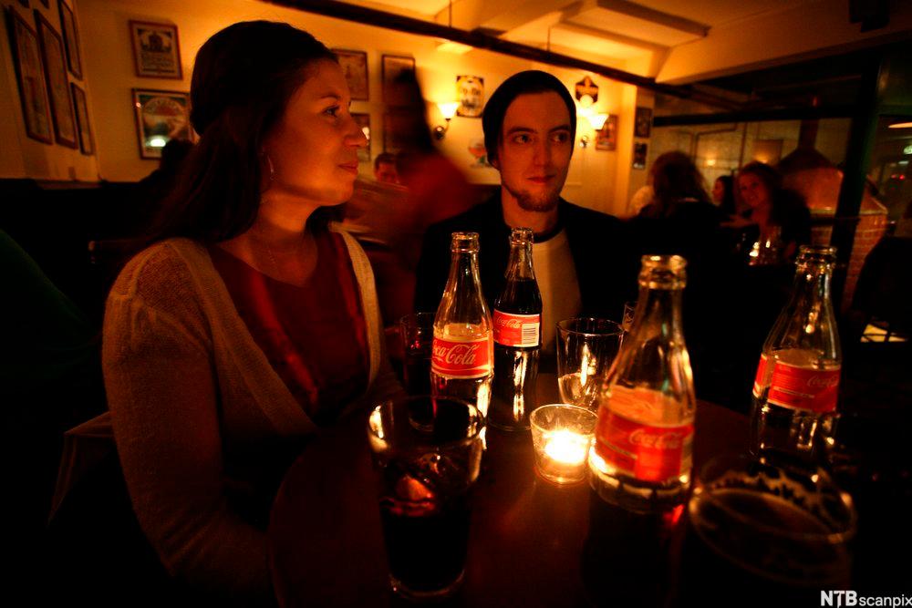 Ungdommar som drikk coca cola på ein utestad. Foto.