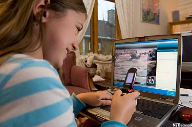 Jente med bærbar pc og mobiltelefon