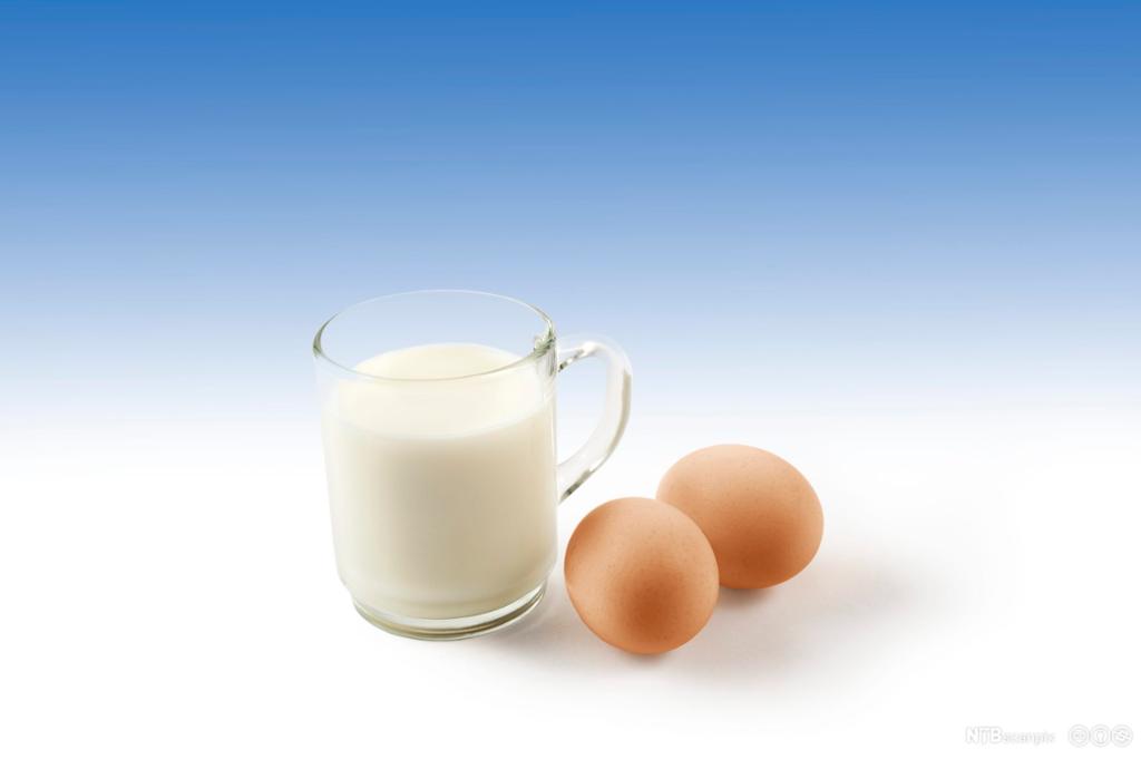 Et glass fylt med melk med to egg ved siden av. Foto.