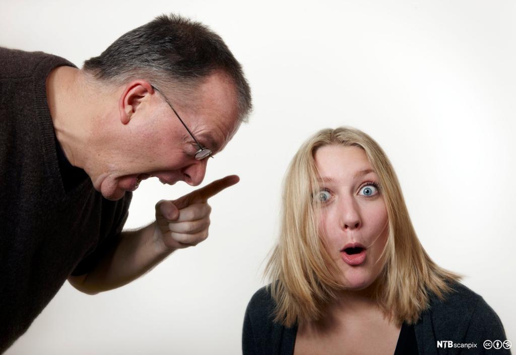 En mann retter finger mot og skriker til en jente som ser overrasket ut. Foto.