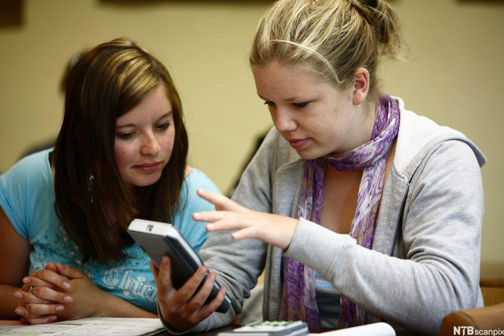  To jenter ser på en kalkulator. Foto.