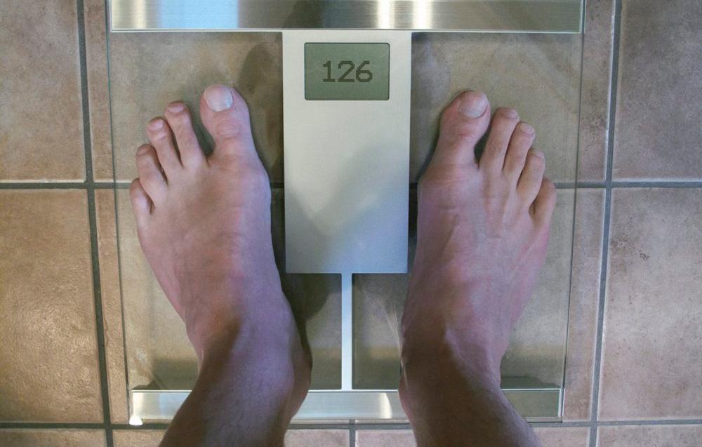 To føter står på ei vekt som viser 126 kg. Foto.
