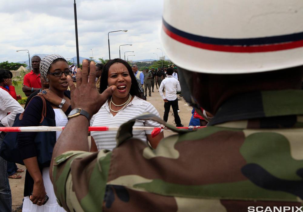 A Nigerian military policeman turns back women at suicide bomber detonation site