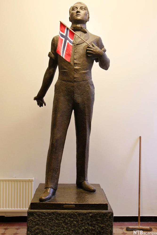 Statue av Henrik Wergeland med flagg. Foto.