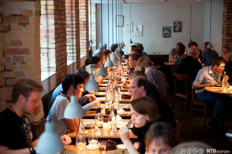 Mange mennesker som spiser i en restaurant. Foto.