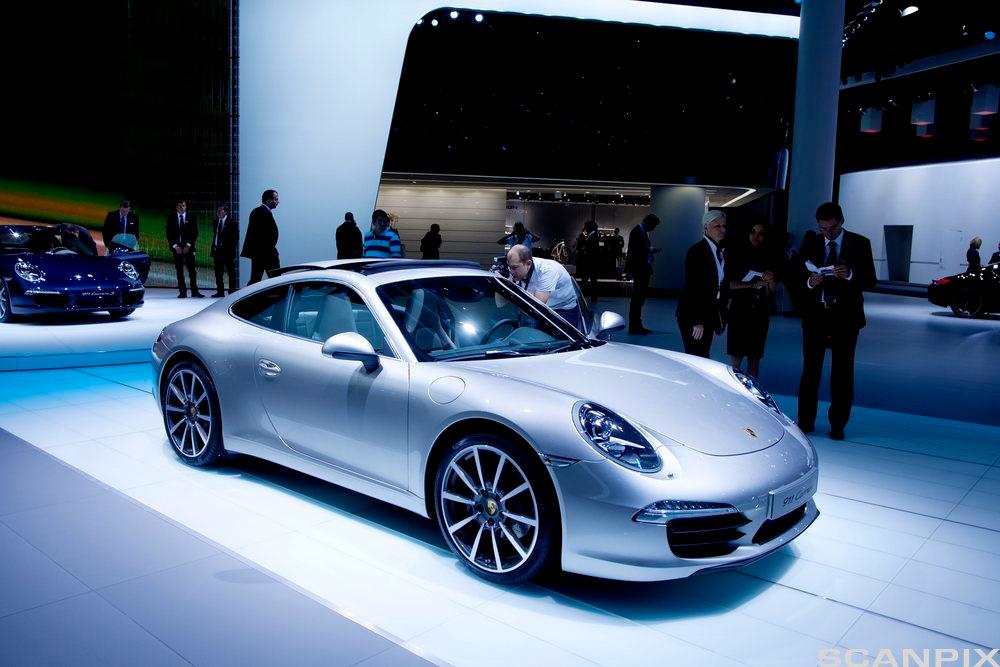 Lys grå Porsche 911 Carrera stilt ut i en stor hall. Foto.
