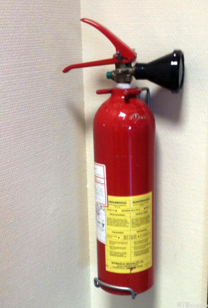 Håndholdt brannslukkingsapparat montert på vegg. Foto.