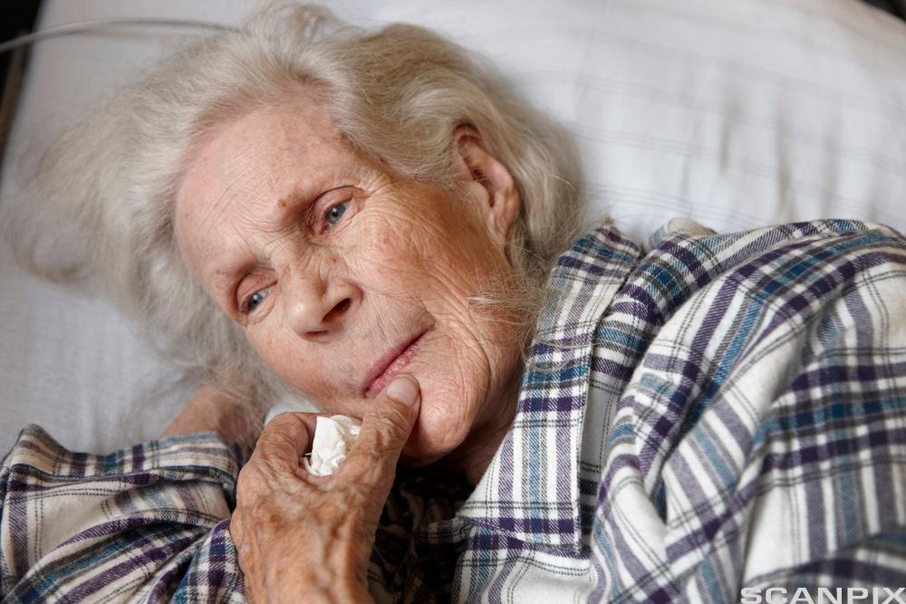 Eldre kvinne som ligger i en seng. Foto.