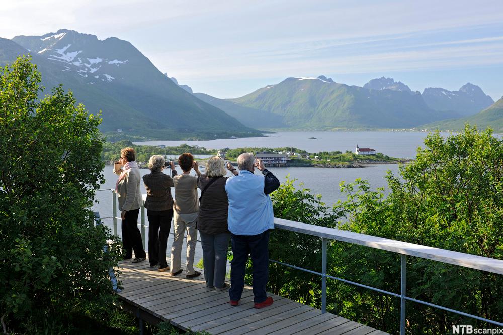 Fem turistar i Lofoten ser på og tek bilete av utsikta. Foto.