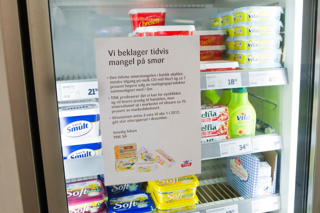 Kjølerom i butikk, med plakat på døra som beklager at butikken er tom for smør.
