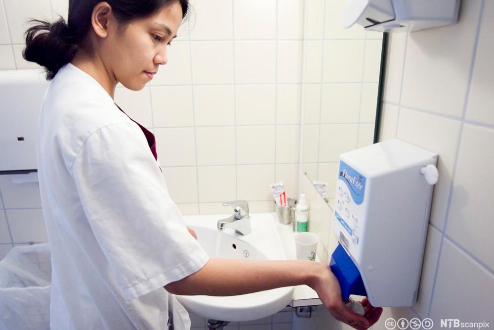 Kvinnelig helsefagarbeider vasker hender. Foto.