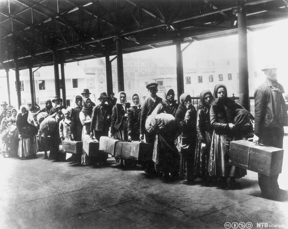 Immigrants queue after arrival at Ellis Island, circa year 1900. Photo.